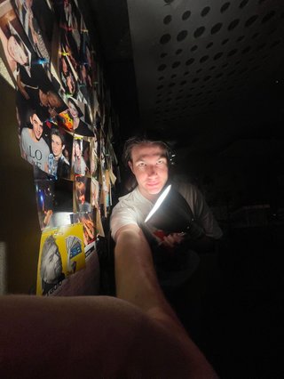 A kinda scary 0.5x selfie of Jim shining a bright lamp directly under their chin