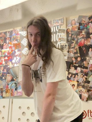 Jim posing suggestively with a finger on their lips in the fbi studio