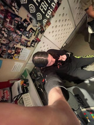 A 0.5x selfie taken from above of Jim in the studio holding up a peace sign.