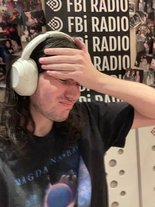 Jim in the studio with their hand on their forehead.
