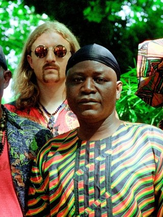 Five members of WITCH standing in front of green trees