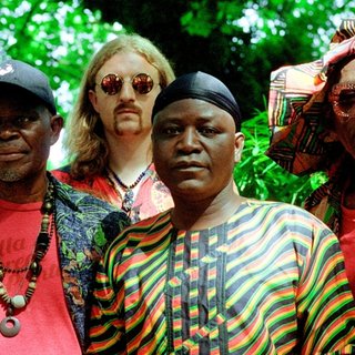 Five members of WITCH standing in front of green trees